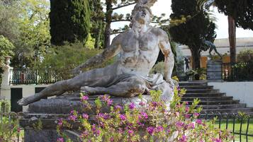 A statue of a reclining figure in a garden setting with steps leading up to it.