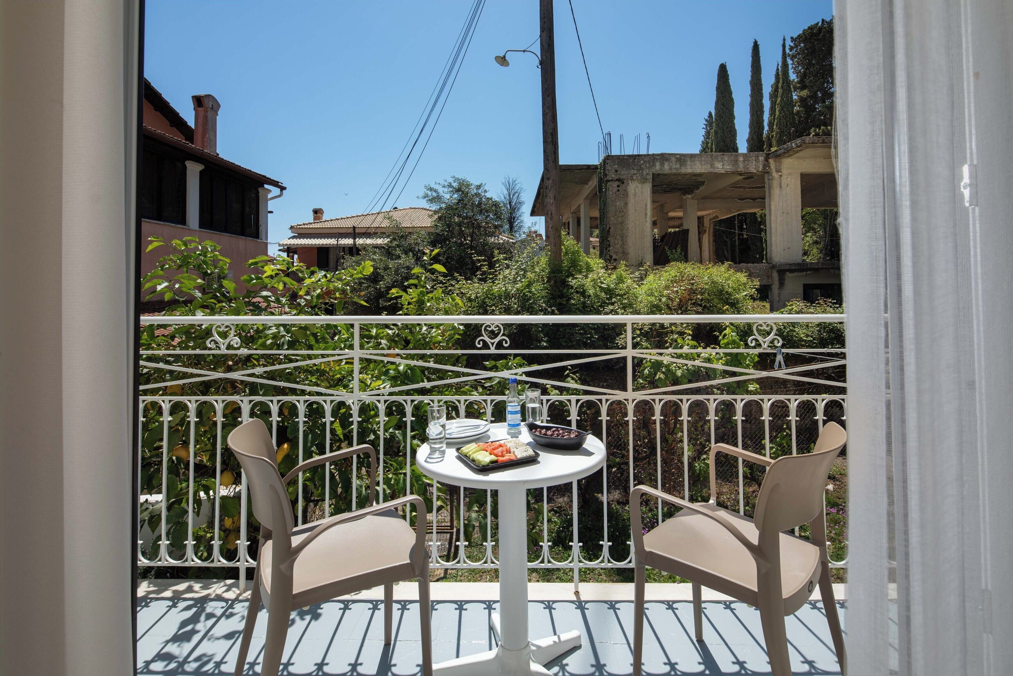 A balcony with two chairs and a table, featuring a view of buildings and greenery.