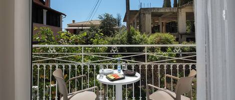 A balcony with two chairs and a table, featuring a view of buildings and greenery.