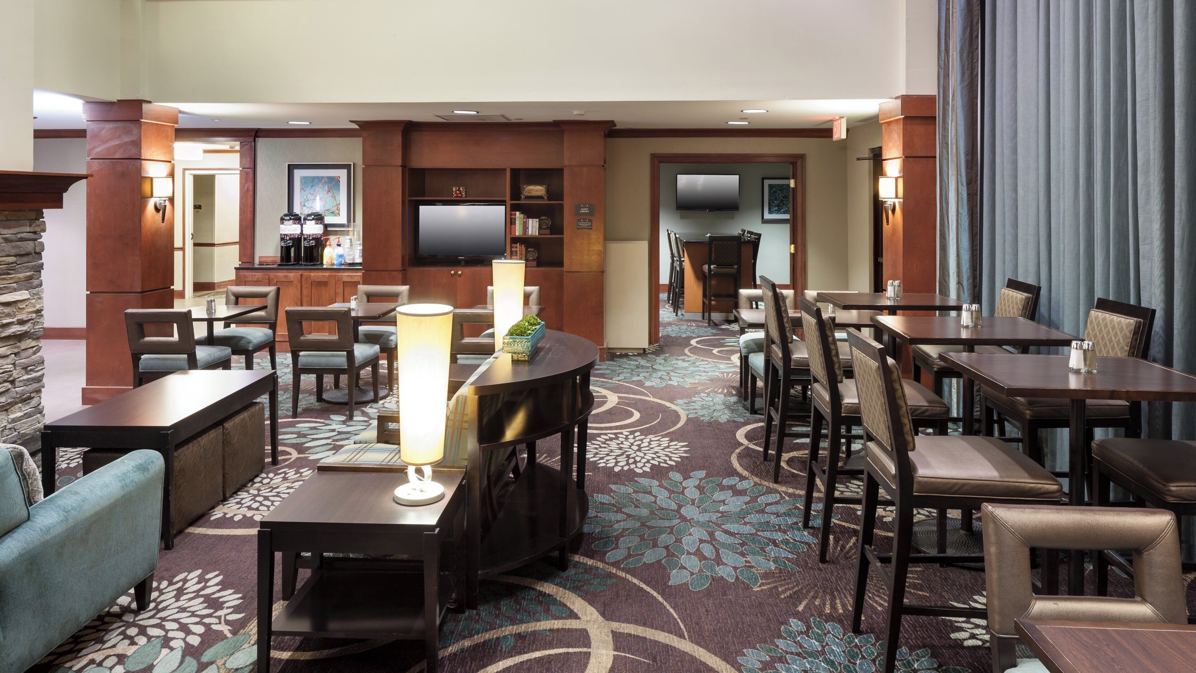 A hotel lobby with a seating area, a coffee station, and a television.