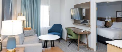 Une chambre d’hôtel équipée d’un lit, d’un bureau, d’une chaise, d’une télévision et d’un canapé.
