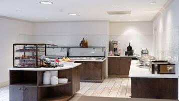 A modern kitchen with a central island, built-in shelves, and a glass display case.