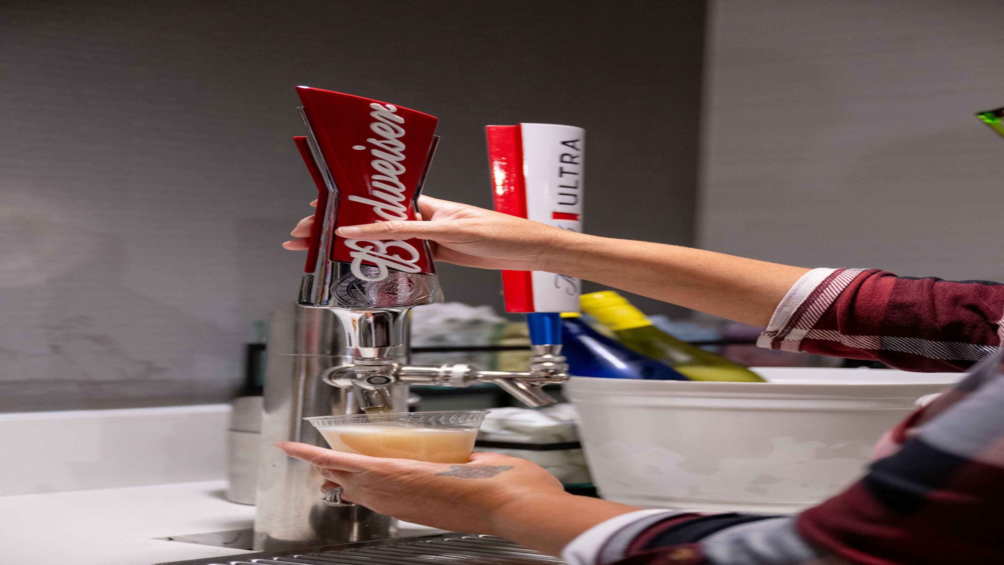 A person pouring a drink from a tap labeled "Blauer" into a glass.