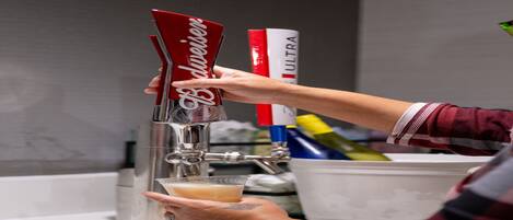 A person pouring a drink from a tap labeled "Blauer" into a glass.