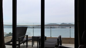 Een balkon met rieten stoelen en uitzicht op zee.