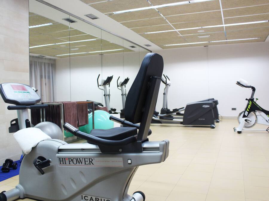 A gym with various exercise equipment including a stationary bike, elliptical, and weight machines.