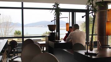 Een moderne eetruimte met uitzicht op een meer en bergen, met een bar en zitgedeelte.