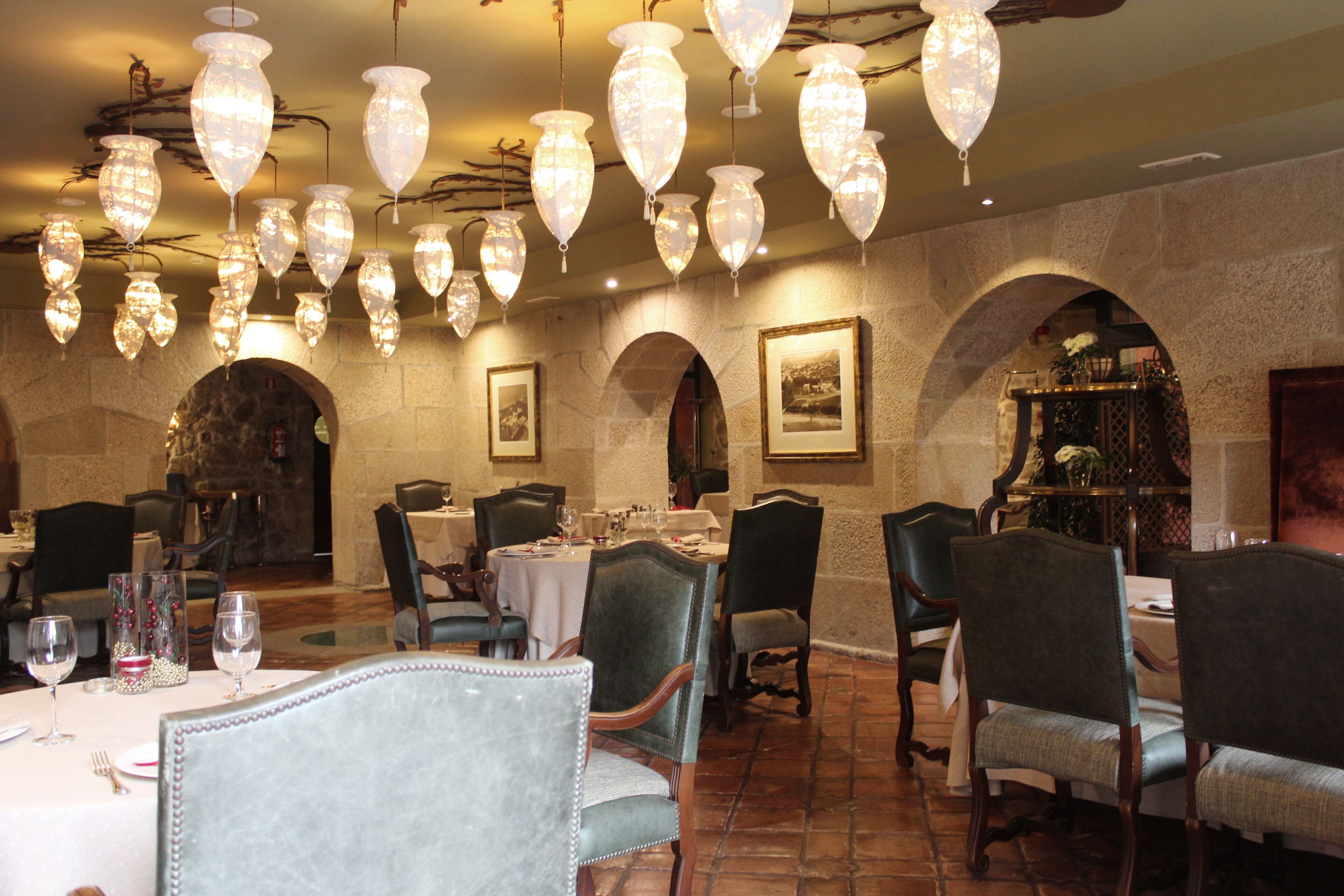 Un restaurante con varias mesas, sillas y candelabros colgantes.