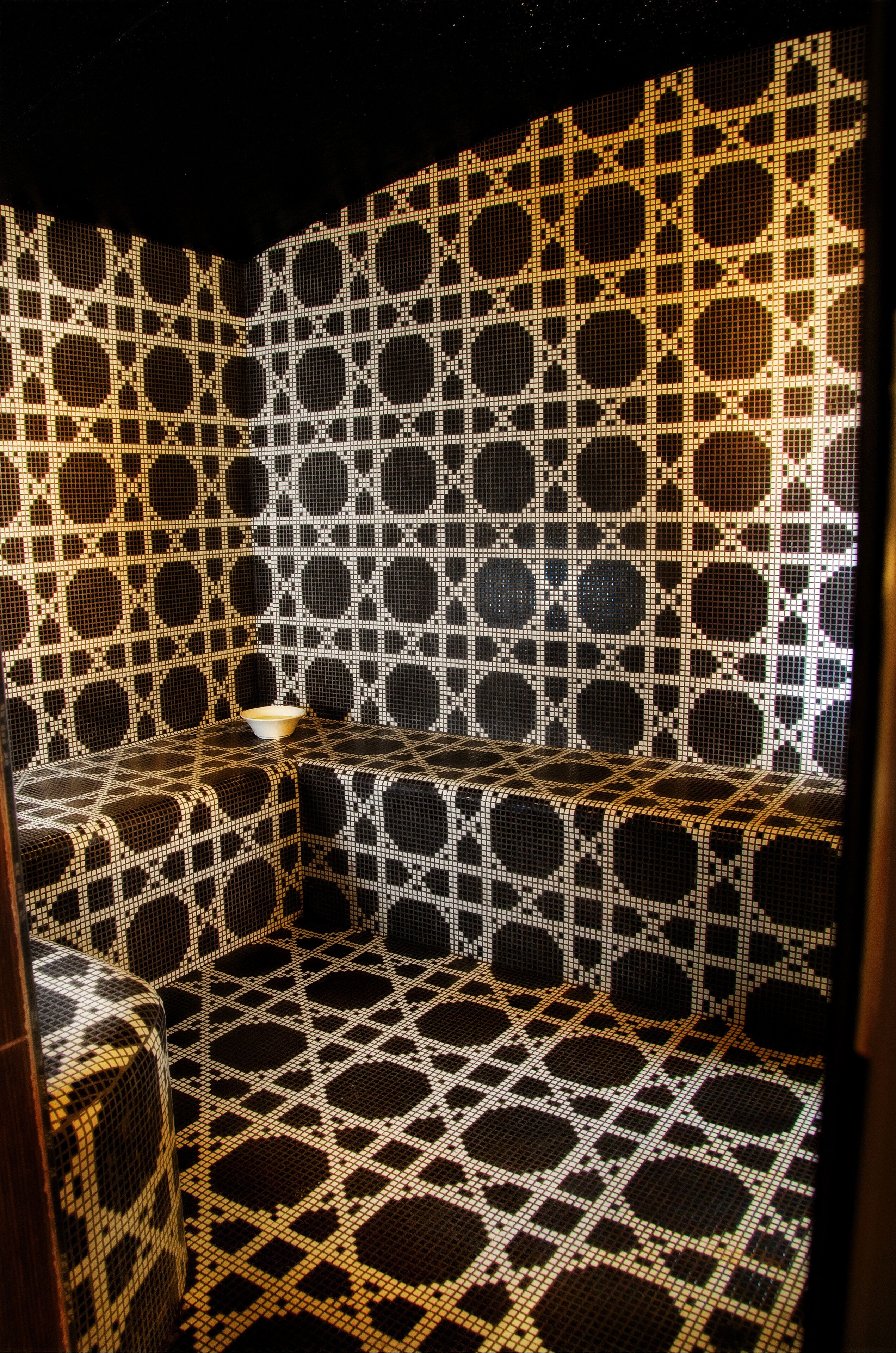 Una habitación con una pared de diseño geométrico y una pequeña mesa con un cuenco.