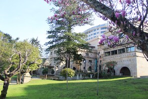 A historic building with a courtyard, stone architecture, and flowering trees.