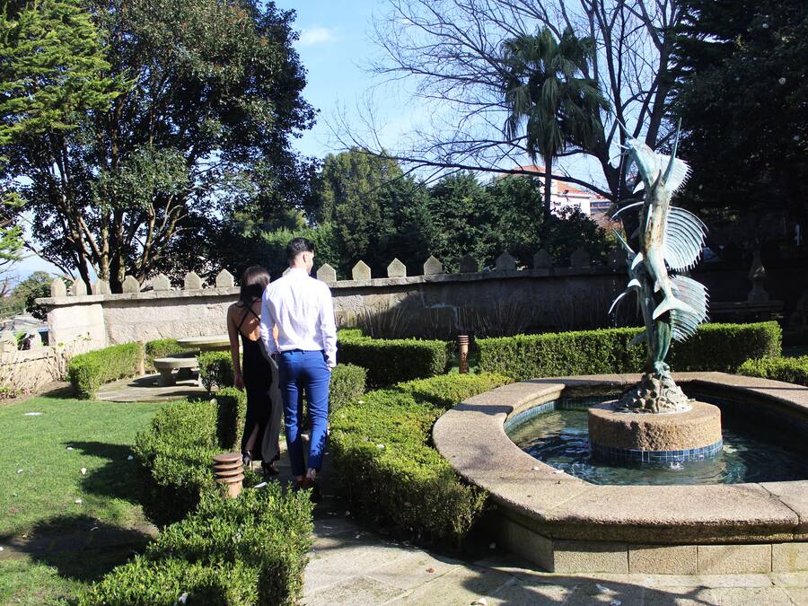 Un jardín con una fuente, setos cuidados y una estatua.