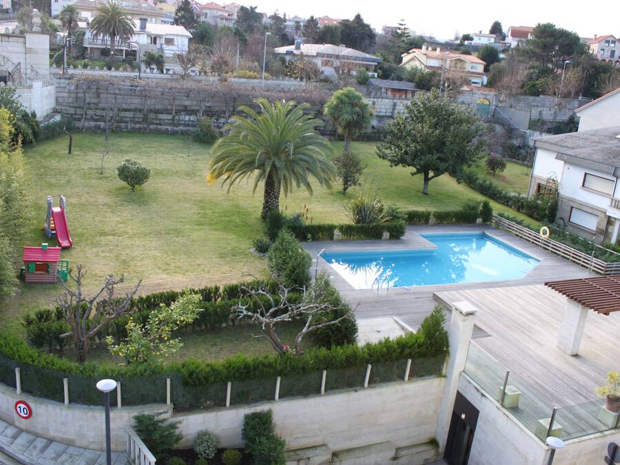 A residential area with a swimming pool, a red slide, and a well-maintained lawn.