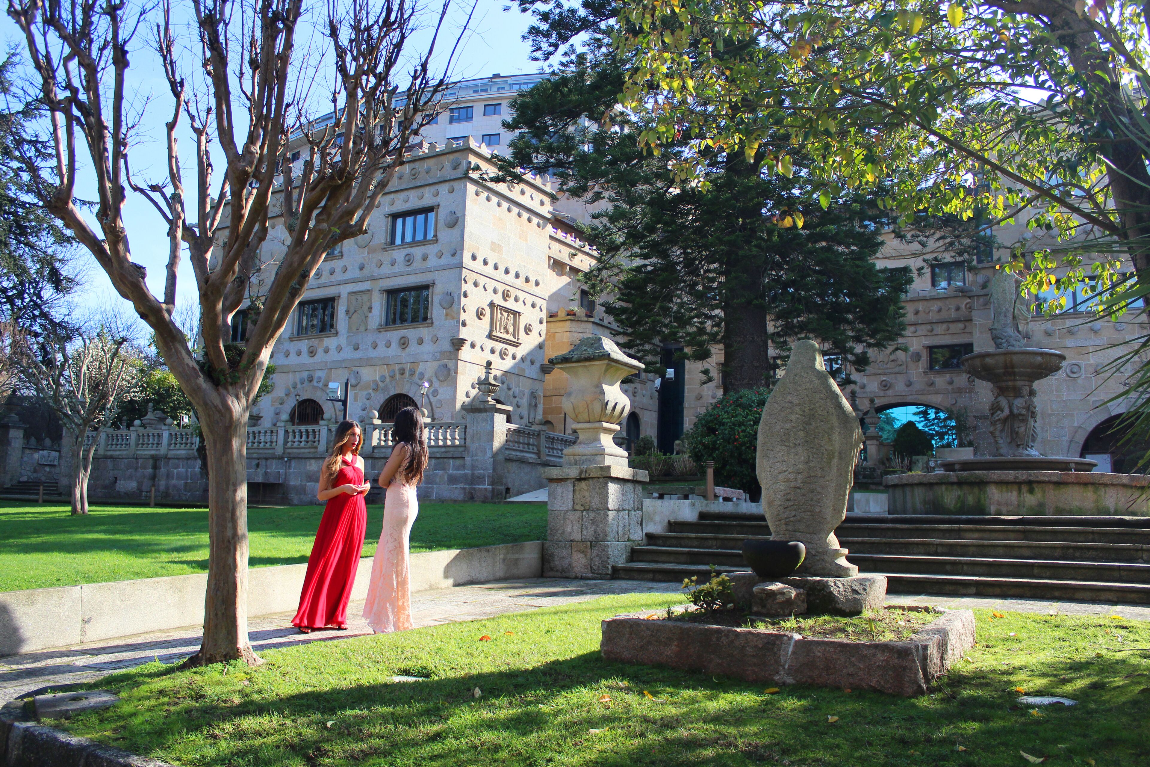 A courtyard with a fountain, a statue, and a building with classical architecture.