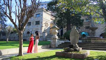 A courtyard with a fountain, a statue, and a building with classical architecture.