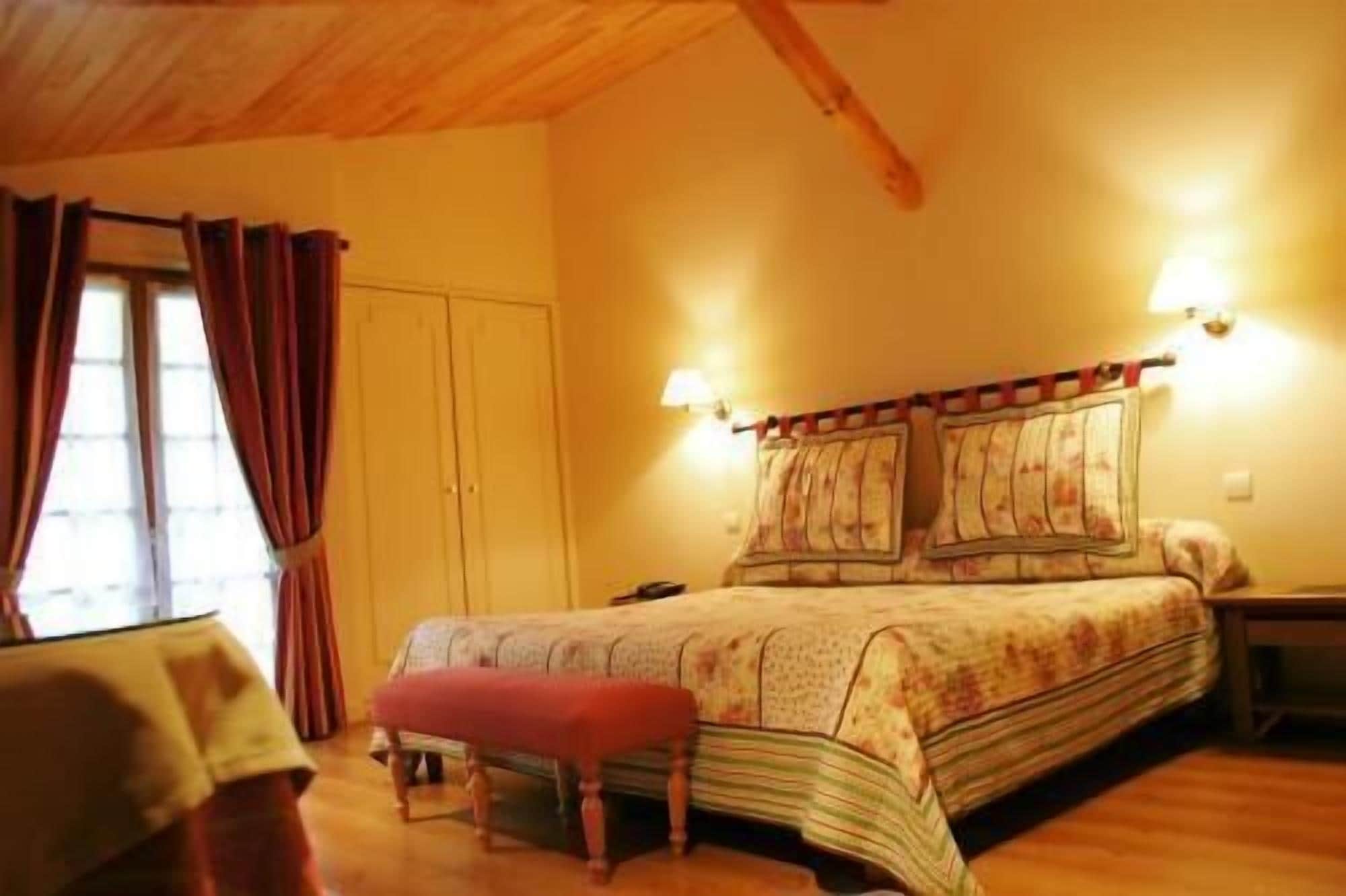 A bedroom with a bed, a nightstand, a lamp, and a window with curtains.
