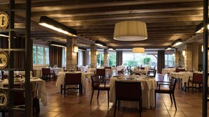 En restaurant med runde borde, stole og en stor hængende lampe.