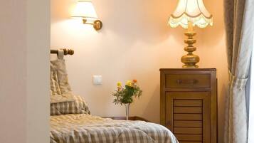 Ein Schlafzimmer mit einem Bett, Nachttischlampen, einem Beistelltisch und einem kleinen Tisch mit einer Pflanze.