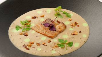 Un plato con salsa cremosa, adornado con hierbas y nueces.