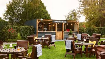 Un bar en un jardín con muebles de madera y un letrero.