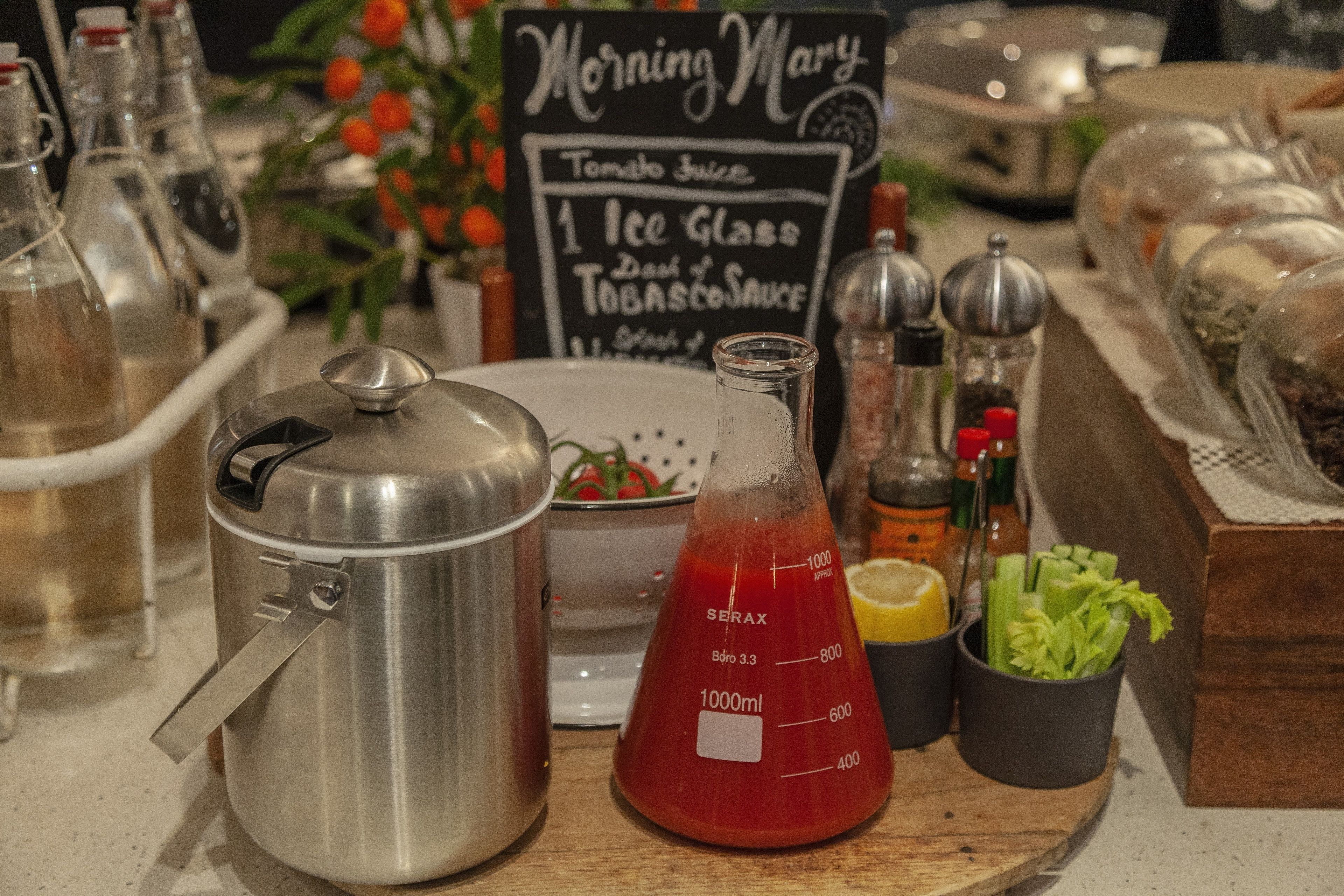 A kitchen counter with cooking equipment, a measuring flask, and a chalkboard menu.