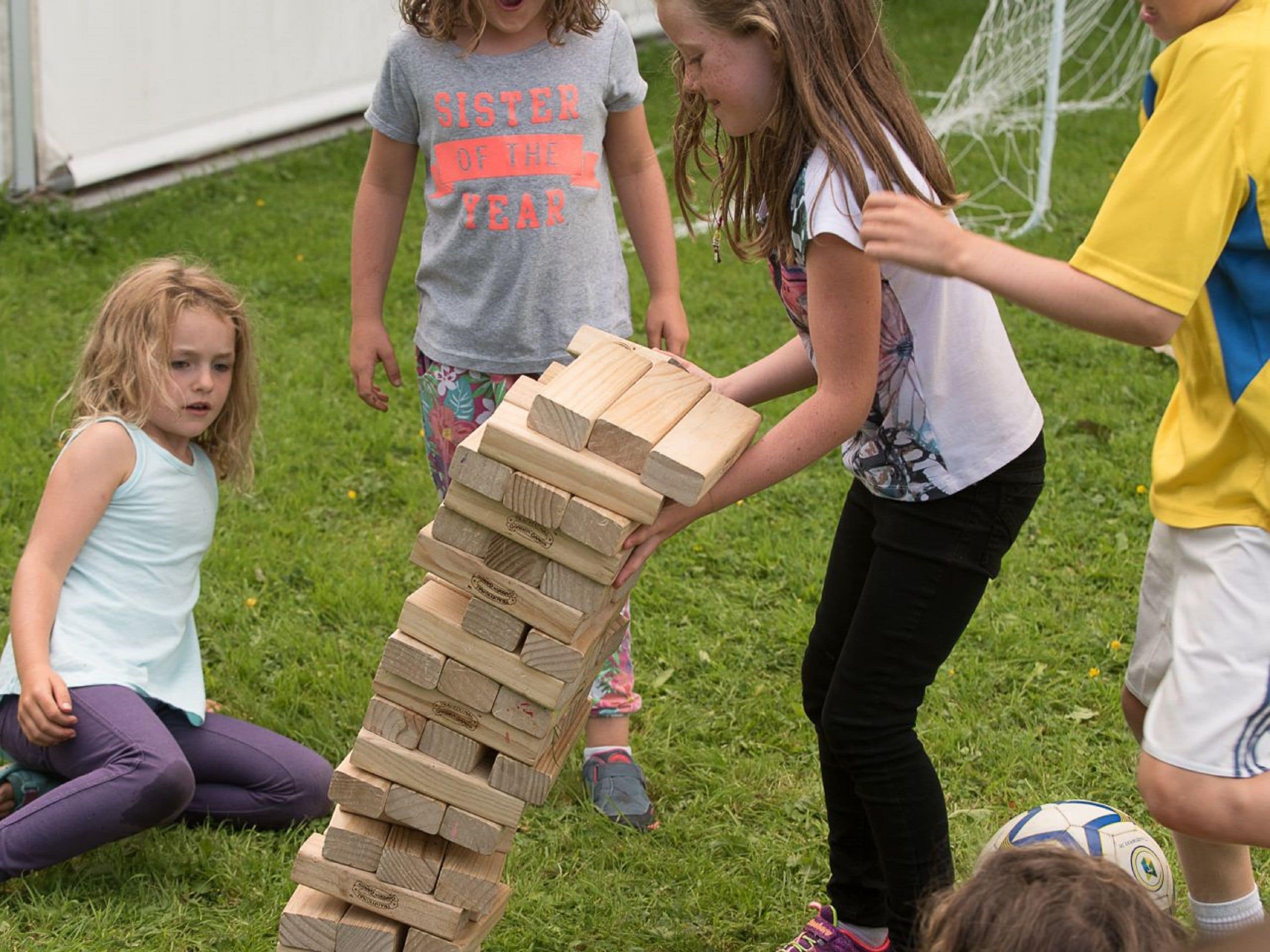 Children playing with wooden blocks on grass.