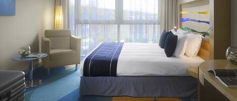 Una habitación de hotel con una cama, una silla, una mesita y un escritorio.