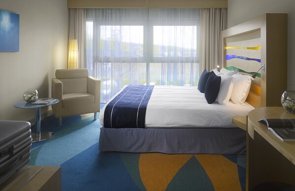 Una habitación de hotel con una cama, una silla, una mesita y un escritorio.