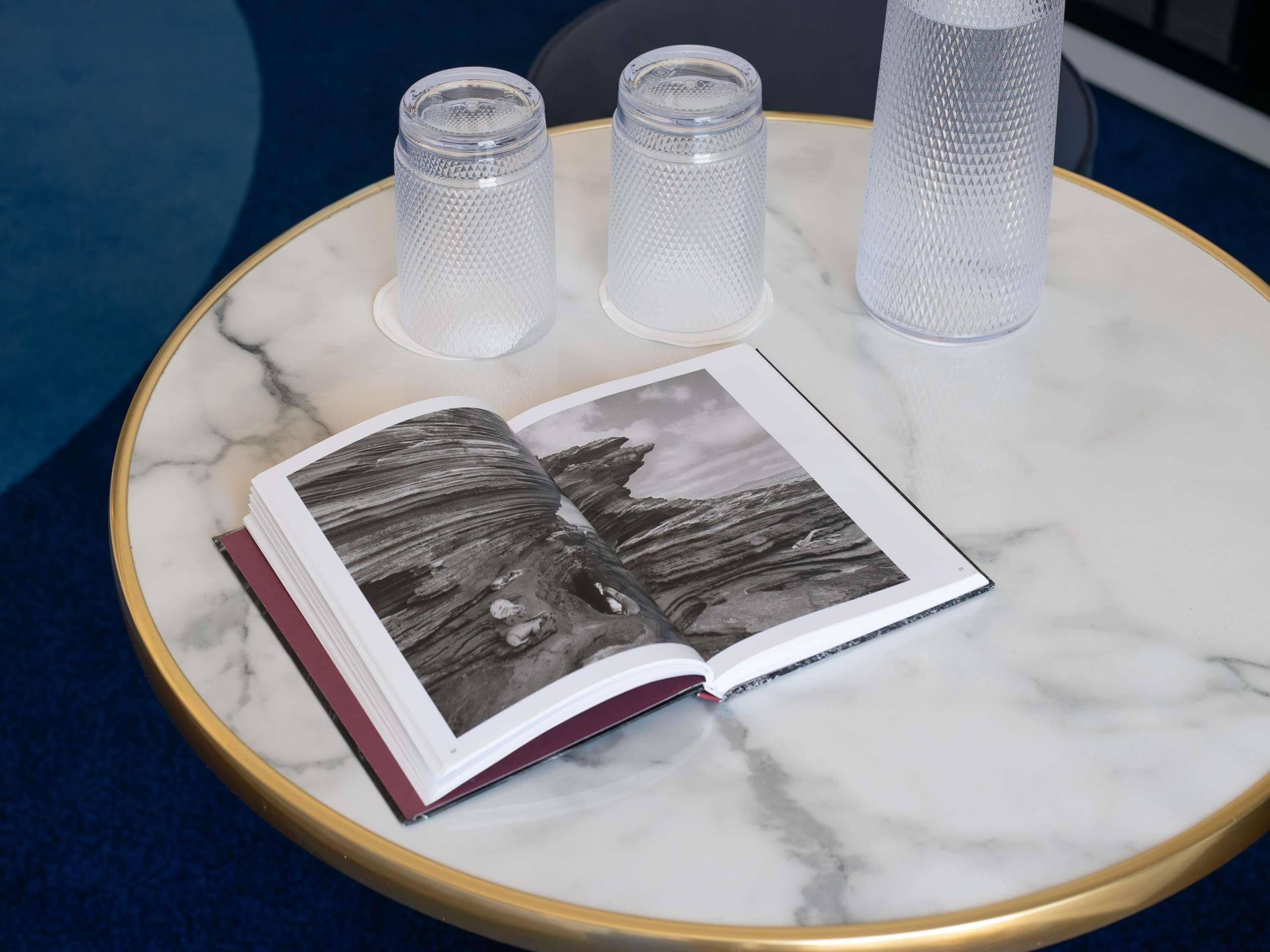 A marble table with a book and three clear glass candle holders.