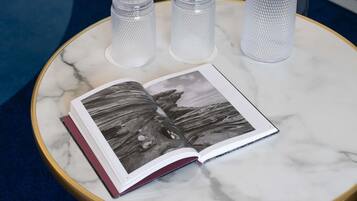 A marble table with a book and three clear glass candle holders.
