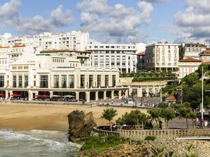 Un hotel frente al mar con vistas a la playa, varios pisos y zonas de estar al aire libre.
