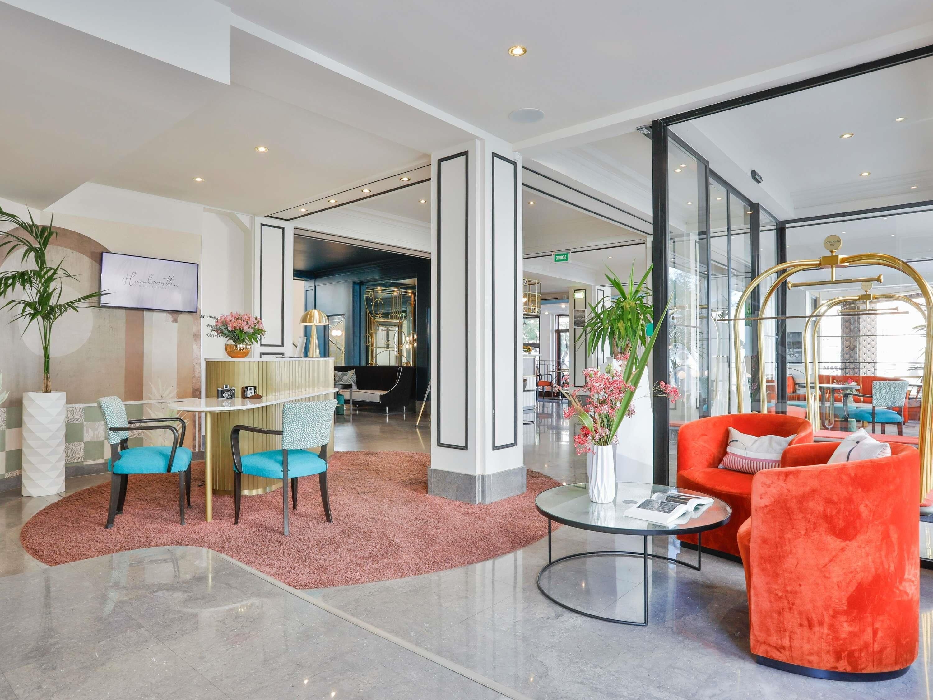 Eine moderne Lobby mit einer Rezeption, einer Sitzecke mit einem roten Sofa und einer Glastrennwand.