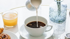 Een ontbijtsetting met een kop koffie, een glas sinaasappelsap, een bord met gebak en een schaal druiven en watermelonschijfjes.