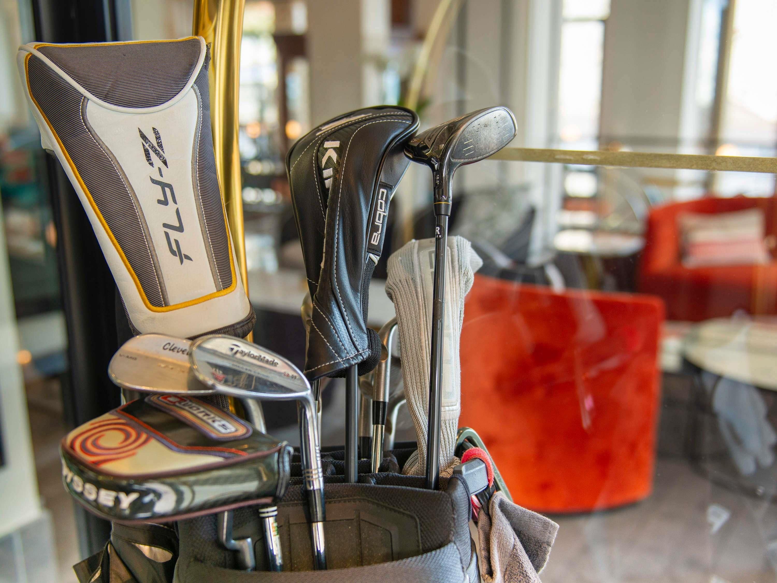 A golf bag with multiple clubs, including a putter and a driver, placed on a table.