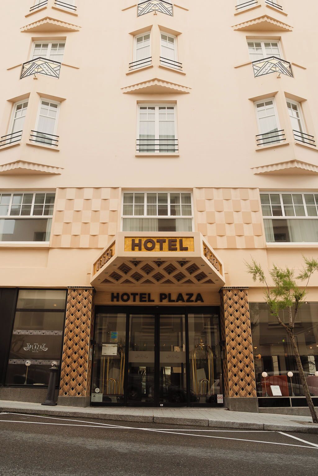 A hotel building with a sign reading "HOTEL PLAZA" and "HOTEL" above the entrance.