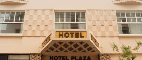 A hotel building with a sign reading "HOTEL PLAZA" and "HOTEL" above the entrance.