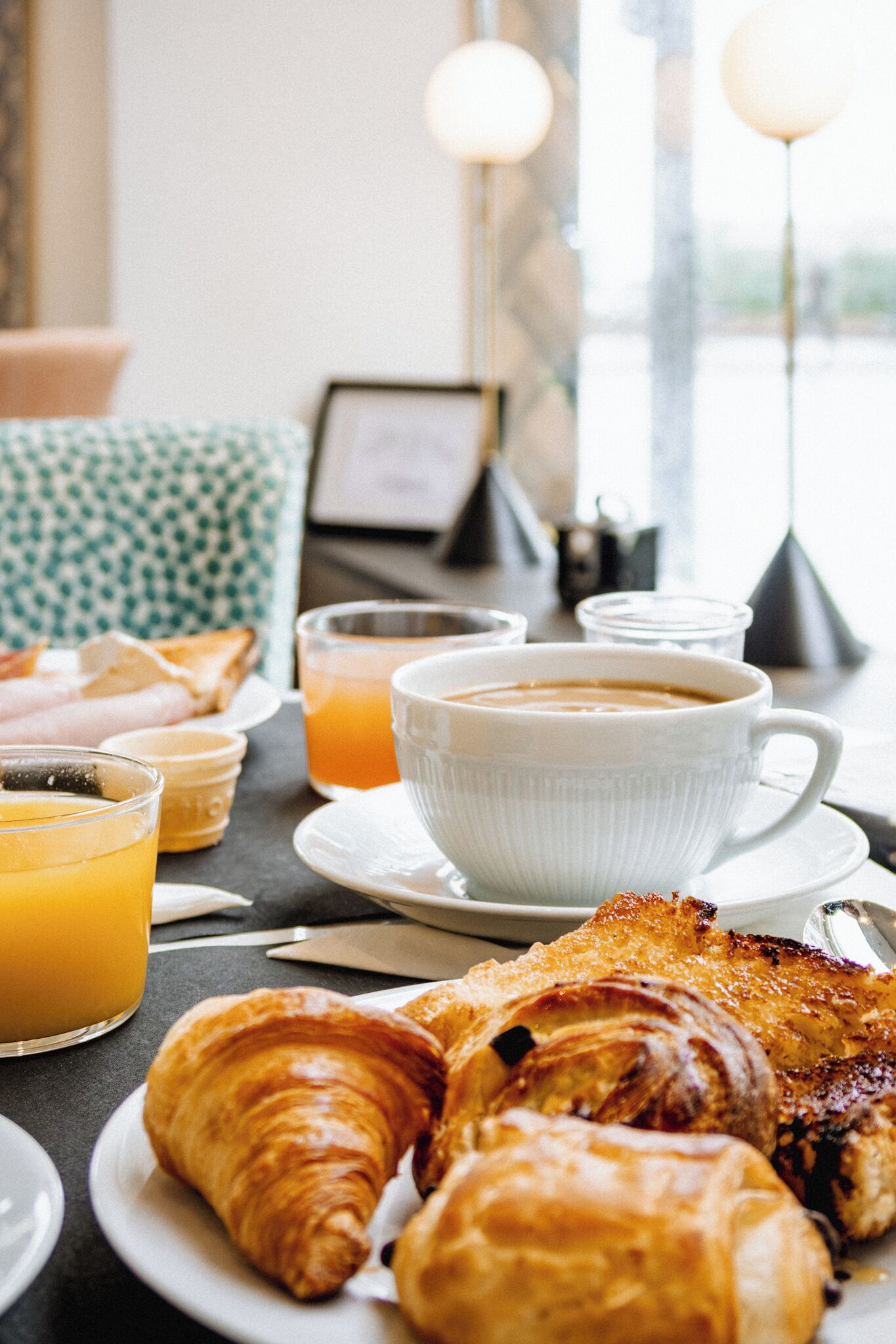 A breakfast setting with croissants, orange juice, and coffee on a table.