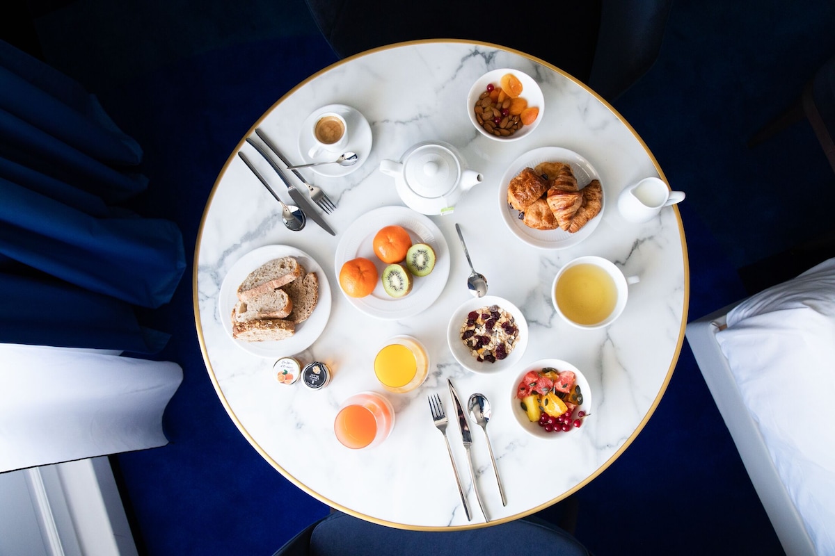 A breakfast table with various food items, including croissants, fruits, and beverages.