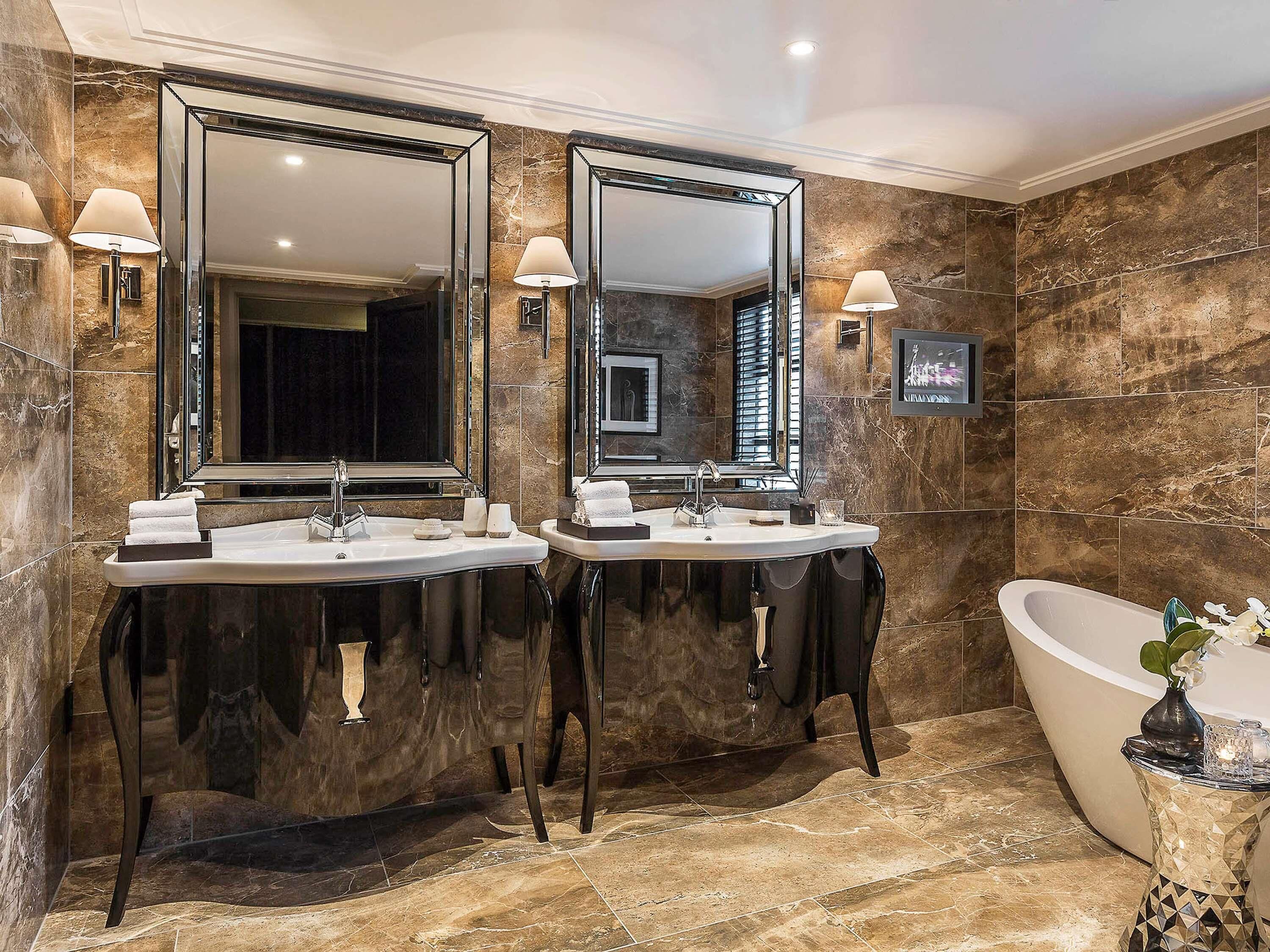 A luxurious bathroom with two sinks, a large mirror, and a freestanding bathtub.