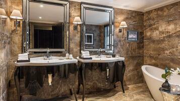 A luxurious bathroom with two sinks, a large mirror, and a freestanding bathtub.