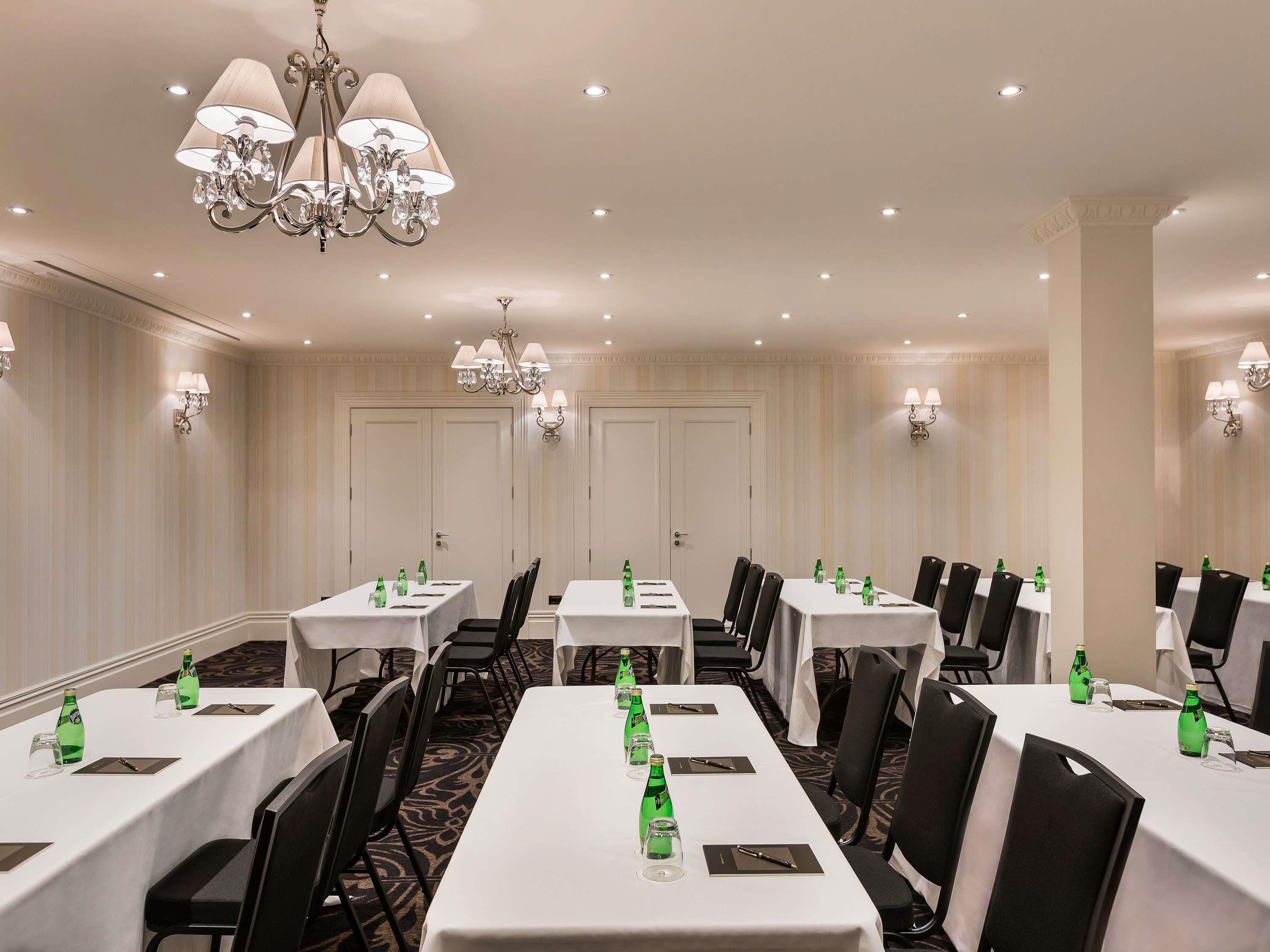 Une salle de conférence équipée de plusieurs tables, de chaises et d’un lustre.