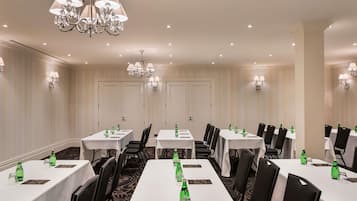 A conference room with multiple tables, chairs, and a chandelier.