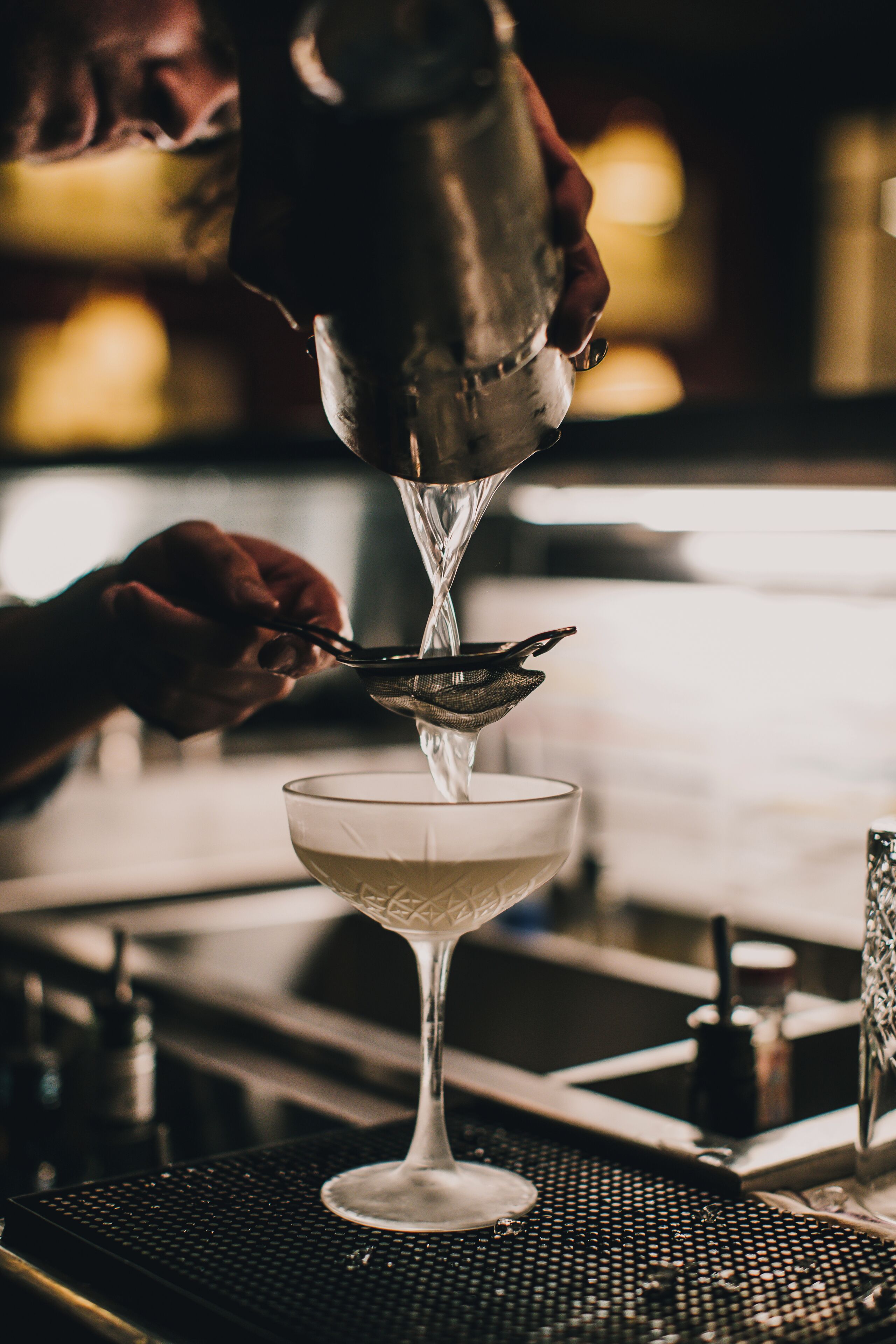 A bartender pouring a drink into a glass.