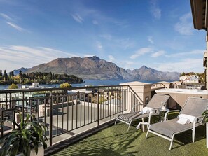 A balcony with a view of mountains and a lake, lounge chairs, and a railing. - Sofitel Queenstown Hotel & Spa (Queenstown)