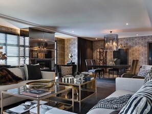 Een moderne woonkamer met een open haard, een eethoek en een kroonluchter.