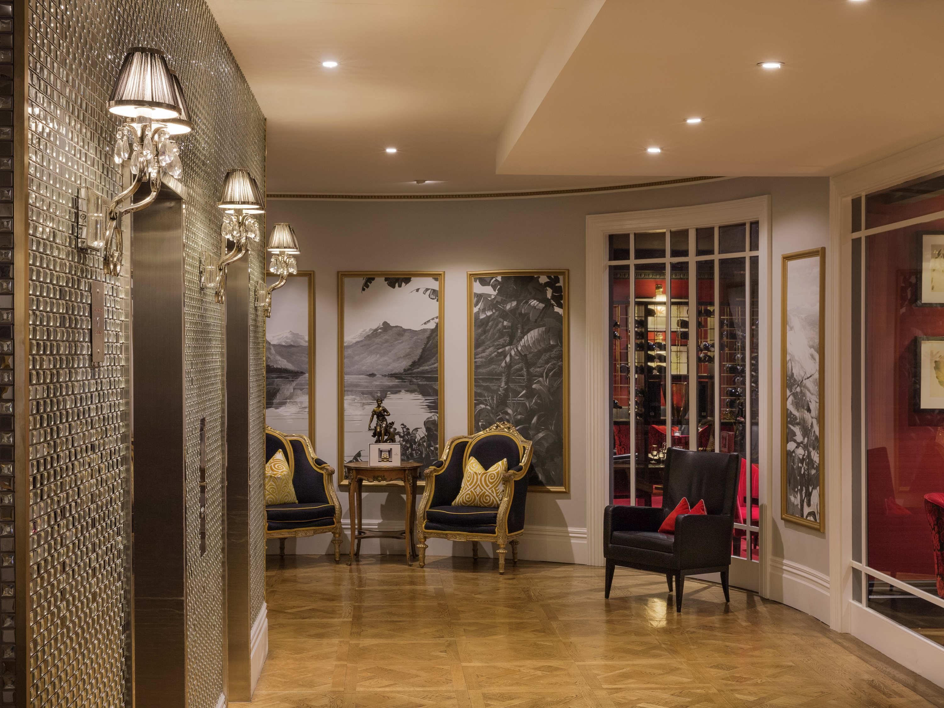 Une pièce avec un mur recouvert de miroirs, une table avec des chaises et un présentoir éclairé de lumière rouge.