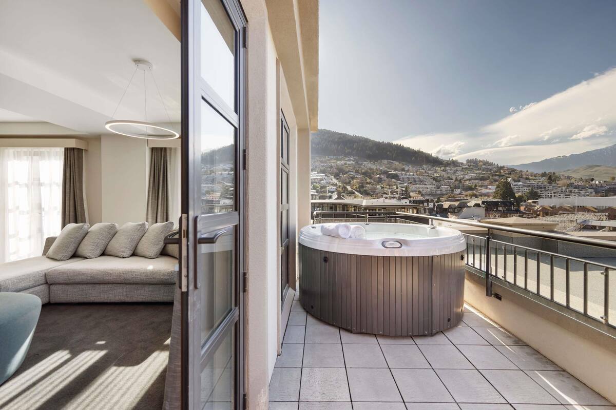 A balcony with a hot tub, a sofa, and a city view.