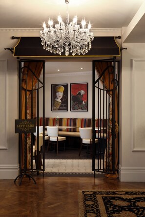 A hotel lobby with a chandelier, a sign reading "LEFT BANK," and a striped bench. - Sofitel Queenstown Hotel & Spa (Queenstown)