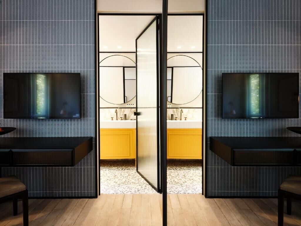 A modern bathroom with a mirror, two sinks, and a television mounted on the wall.