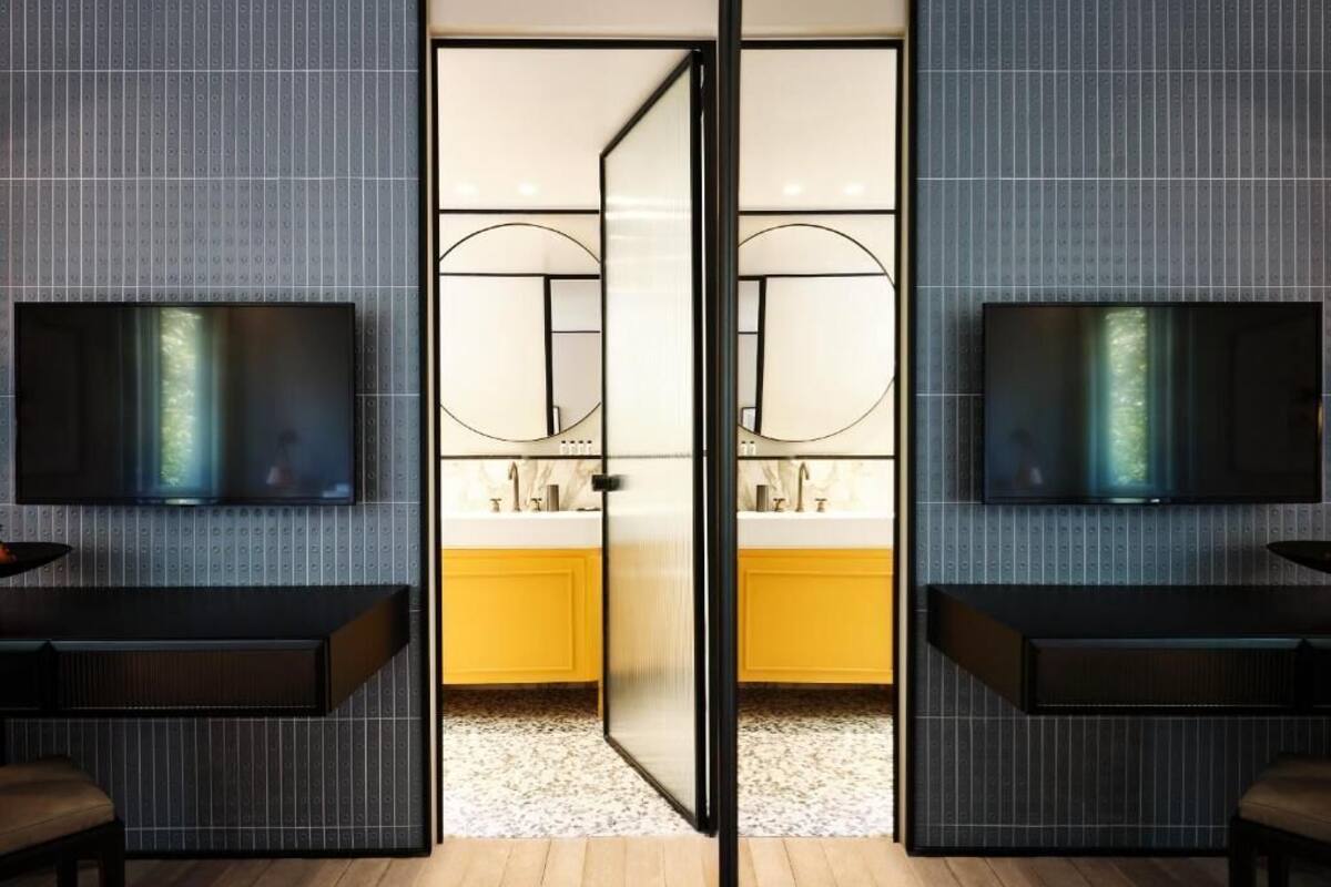 Une salle de bain moderne avec un miroir, deux lavabos et un téléviseur fixé au mur.