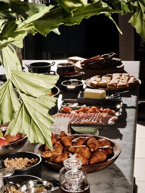 A buffet table with various food items including pastries, meats, and cheeses.